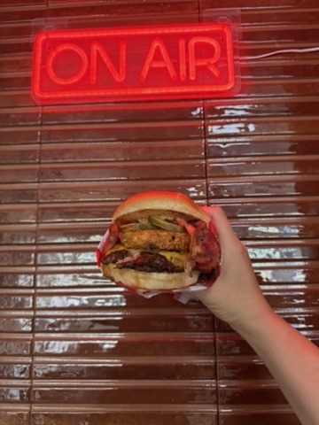 Burger trzymany pod neonem On Air
